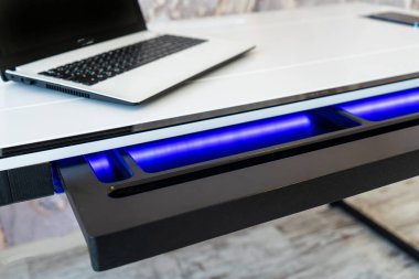 Mavi yıldırımlı açık ahşap çekmece ofis masasının üst görüntüsü. Işıklı modern ofis masası