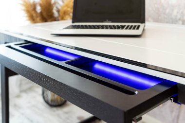 Mavi yıldırımlı açık ahşap çekmece ofis masasının üst görüntüsü. Işıklı modern ofis masası