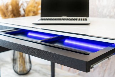 Mavi yıldırımlı açık ahşap çekmece ofis masasının üst görüntüsü. Işıklı modern ofis masası