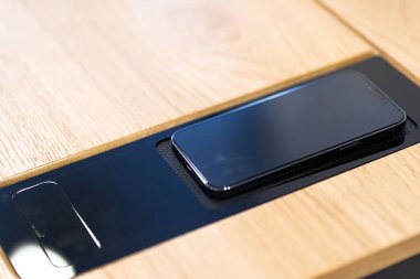 Kablosuz şarj masalı ahşap masa. Cep telefonları, kulaklıklar ve tabletler için kablosuz şarj cihazı. Ofisteki kablosuz şarj istasyonu.