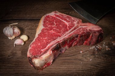 Koyu bir tahta üzerinde baharatlı çiğ biftek, taş ya da beton arka plan. Kopyalama alanı olan üst görünüm.
