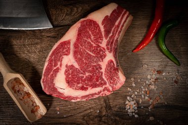 Kalın Raw T-Bone bifteği. Kurumuş Raw T-bone ya da biftek bifteği, yabandomuzunu otlarla kesmek ve arka planda tuz. Üst görünüm ve kopyalama alanı.