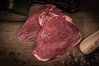 Ahşap tahtada çiğ biftek ve ahşap arka planda kekik.