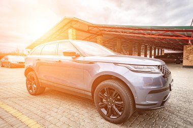 Predatory car headlight with blue lights and hood of powerful grey blue car sports car with matte grey paint and wheel