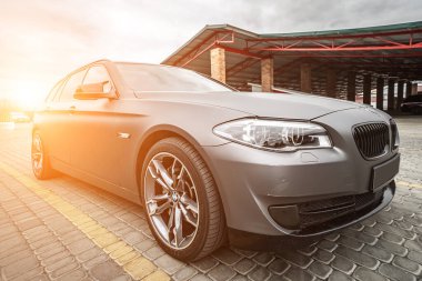 Predatory car headlight with blue lights and hood of powerful grey blue car sports car with matte grey paint and wheel