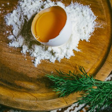 Mermer masanın üzerindeki un yığınının içinde taze yumurta var. Pizza ya da makarna için hamur. mesaj için yer. Üst Manzara. dikey resim.