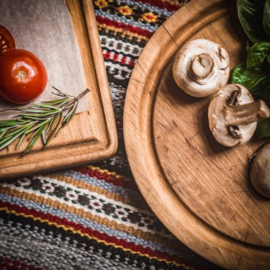 Şef, ellerinde İtalyan ve Akdeniz mutfağı malzemeleriyle çevrili taze olgun domatesleri doğruyor.