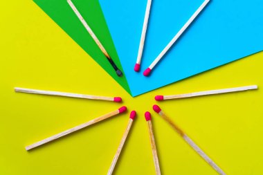 Başarı, yenilgi, başarı. Mutluluk kavramı. Sarı arka plandaki eşleşmeler. Normal kibritler arasında yanmış koyu bir kibrit. Yangınlar komşularını ateşler, fikirler ve ilham için bir metafor