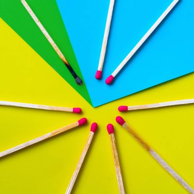 Başarı, yenilgi, başarı. Mutluluk kavramı. Sarı arka plandaki eşleşmeler. Normal kibritler arasında yanmış koyu bir kibrit. Yangınlar komşularını ateşler, fikirler ve ilham için bir metafor