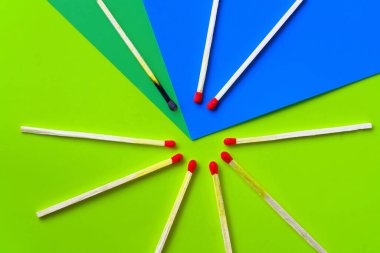 Başarı, yenilgi, başarı. Mutluluk kavramı. Sarı arka plandaki eşleşmeler. Normal kibritler arasında yanmış koyu bir kibrit. Yangınlar komşularını ateşler, fikirler ve ilham için bir metafor