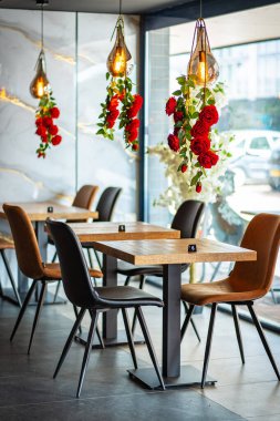 Modern ve zarif bir yemek alanı sunan güzel tasarlanmış bir restoran iç mekanı. Uzay, ahşap sandalyeler ve cam kaplamalı masalar da dahil olmak üzere çağdaş mobilyalara sahip..