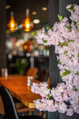 Modern ve zarif bir yemek alanı sunan güzel tasarlanmış bir restoran iç mekanı. Uzay, ahşap sandalyeler ve cam kaplamalı masalar da dahil olmak üzere çağdaş mobilyalara sahip..