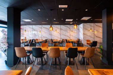 Konforlu ve modern kafe içi ahşap mobilyalar, sıcak ışıklandırma ve sokağa bakan büyük pencerelerle, davetkar bir atmosfer yaratıyor.