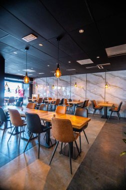 Konforlu ve modern kafe içi ahşap mobilyalar, sıcak ışıklandırma ve sokağa bakan büyük pencerelerle, davetkar bir atmosfer yaratıyor.