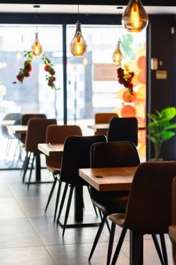 Konforlu ve modern kafe içi ahşap mobilyalar, sıcak ışıklandırma ve sokağa bakan büyük pencerelerle, davetkar bir atmosfer yaratıyor.