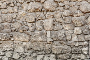 Bej, ahşap ve kahverengi taşlardan yapılmış eski kaba panoramik taş duvar.