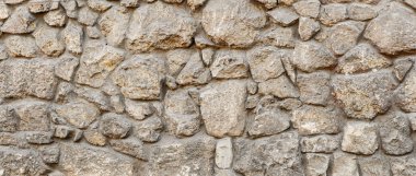 Bej, ahşap ve kahverengi taşlardan yapılmış eski kaba panoramik taş duvar.