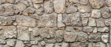 Bej, ahşap ve kahverengi taşlardan yapılmış eski kaba panoramik taş duvar.