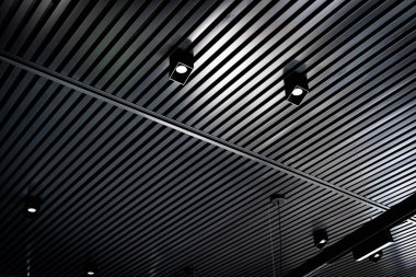 Bottom view of lath ceiling with spot lights. Abstract modern architecture or interior background in black and white with geometric structure. clipart