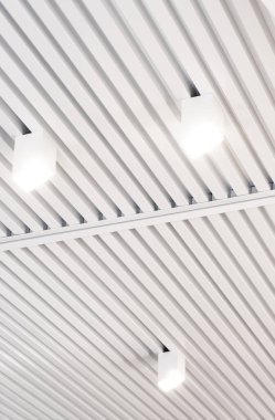 Modern bir depoda parlak ışıkları olan bir tavan, alışveriş merkezi binası, ofis veya diğer ticari gayrimenkul eşyaları. Tavanın altındaki raylarda LED ışıkları