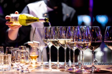 Barmen kırmızı şarabı bardaklara doldurur.