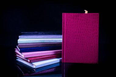 Different colour notebooks on a black background clipart