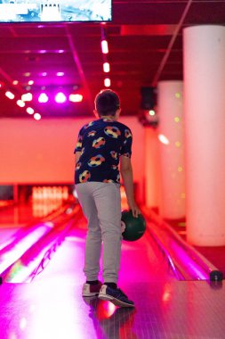 Mutlu genç çocuk bowling oynarken eğleniyor ve tezahürat yapıyor.
