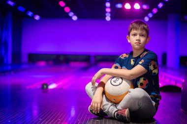 Mutlu genç çocuk bowling oynarken eğleniyor ve tezahürat yapıyor.