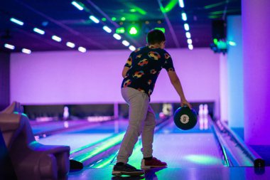 Mutlu genç çocuk bowling oynarken eğleniyor ve tezahürat yapıyor.
