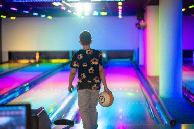 Mutlu genç çocuk bowling oynarken eğleniyor ve tezahürat yapıyor.