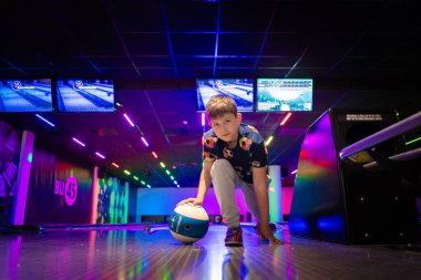 Mutlu genç çocuk bowling oynarken eğleniyor ve tezahürat yapıyor.