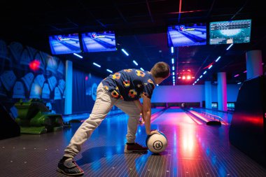 Küçük çocuk eğleniyor ve bowling oynuyor.