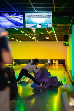 Mutlu genç kız bowling oynarken eğleniyor ve tezahürat yapıyor.