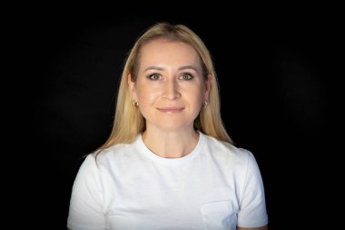 Beyaz tişörtlü, güzel saçlı, sarışın bir kadının portresi. Güzel bir kadın stüdyoda kameraya bakıyor..