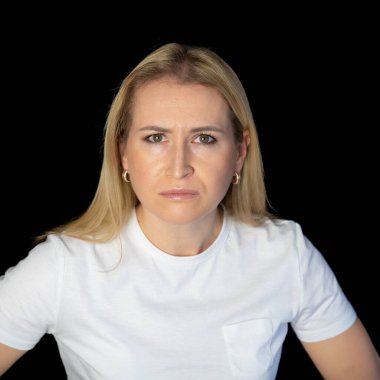 Beyaz arka planda duran genç sarışın kadın şüpheci ve gergin, yüzünde çapraz kollu tasvip etmeyen ifade. negatif kişi.