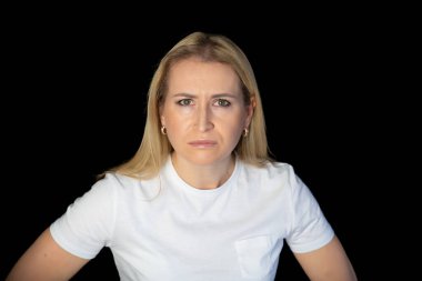 Beyaz arka planda duran genç sarışın kadın şüpheci ve gergin, yüzünde çapraz kollu tasvip etmeyen ifade. negatif kişi.