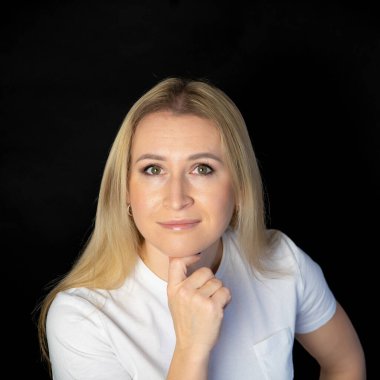 Çekici sarışın, parlak, beyaz tişörtlü, genç bir kadının fotoğrafı. Alnında boş boş boş duran, izole edilmiş siyah arka plan gülümsemesi.