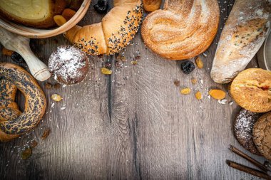 Fırın, çeşitli ekmek çeşitleri. Ekmek ruloları, baget, bagel, tatlı çörek ve kruvasan yukarıdan yakalanır (düz yatak). Siyah arkaplan, bedava kopyalama alanı. Yatay pankart düzeni.