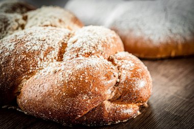 Enfes geleneksel pan de muerto ya da geleneksel siyah arka plan ve Meksika tarzında kilden bir tabakta şekerle süslenmiş ölü ekmek..