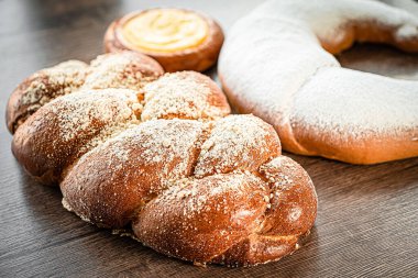 Enfes geleneksel pan de muerto ya da geleneksel siyah arka plan ve Meksika tarzında kilden bir tabakta şekerle süslenmiş ölü ekmek..