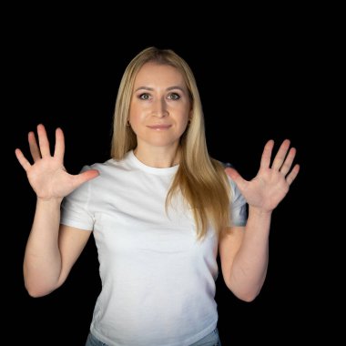 Siyah arka planda duran beyaz tişörtlü genç sarışın kadın parmaklarını göstererek rakamları gösteriyor. On numara, on parmak.