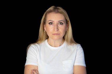 Beyaz arka planda duran genç sarışın kadın şüpheci ve gergin, yüzünde çapraz kollu tasvip etmeyen ifade. negatif kişi.