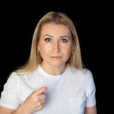 Beyaz arka planda duran genç sarışın kadın şüpheci ve gergin, yüzünde çapraz kollu tasvip etmeyen ifade. negatif kişi.