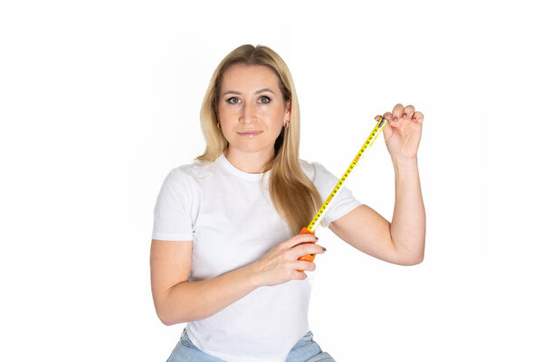 Белая блондинка держит измерительную ленту. Включить измерительную ленту в женской руке. Концепция здания