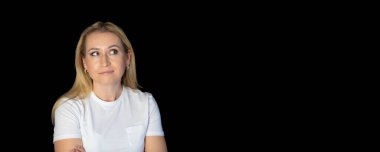 Çekici sarışın, parlak, beyaz tişörtlü, genç bir kadının fotoğrafı. Alnında boş boş boş duran, izole edilmiş siyah arka plan gülümsemesi.