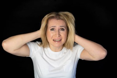 Beyaz arka planda duran genç sarışın kadın şüpheci ve gergin, yüzünde çapraz kollu tasvip etmeyen ifade. negatif kişi.