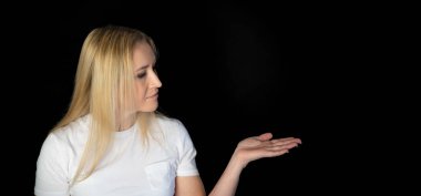Çekici sarışın, parlak, beyaz tişörtlü, genç bir kadının fotoğrafı. Alnında boş boş boş duran, izole edilmiş siyah arka plan gülümsemesi.