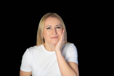Kadının dişleri ağrır, dişlerine dokunur ve acı veren rahatsızlıktan kaşlarını çatar, siyah arka planda durur..
