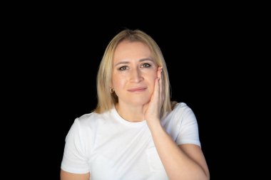 Kadının dişleri ağrır, dişlerine dokunur ve acı veren rahatsızlıktan kaşlarını çatar, siyah arka planda durur..