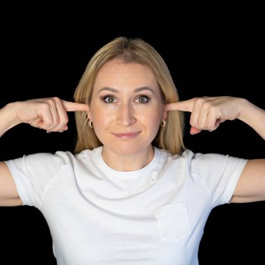 Sinirli genç sarışın kadın hoş olmayan sesler, bilgiler ya da bağırışlar duymamak için kulaklarını kapatıyor.
